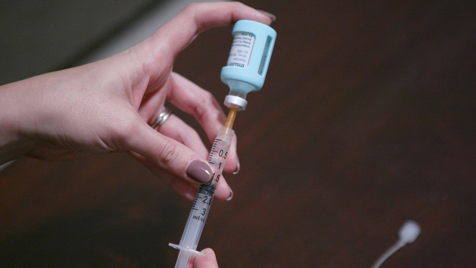 Close up of Lizzie's hand filling a syringe with insulin